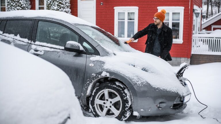 Man charging electric cars in Norway winter.