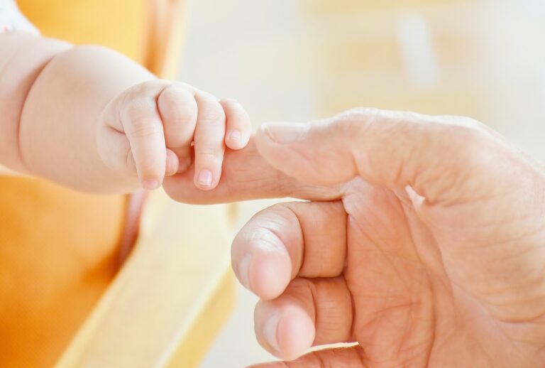 Baby holding a parent's finger.