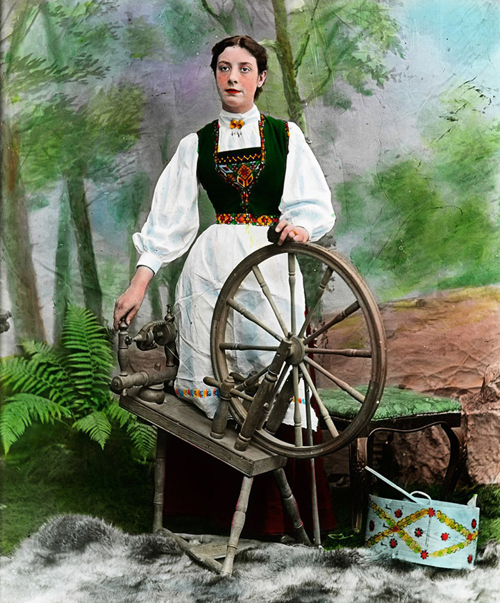 Norwegian woman in the national costume with a spinning wheel