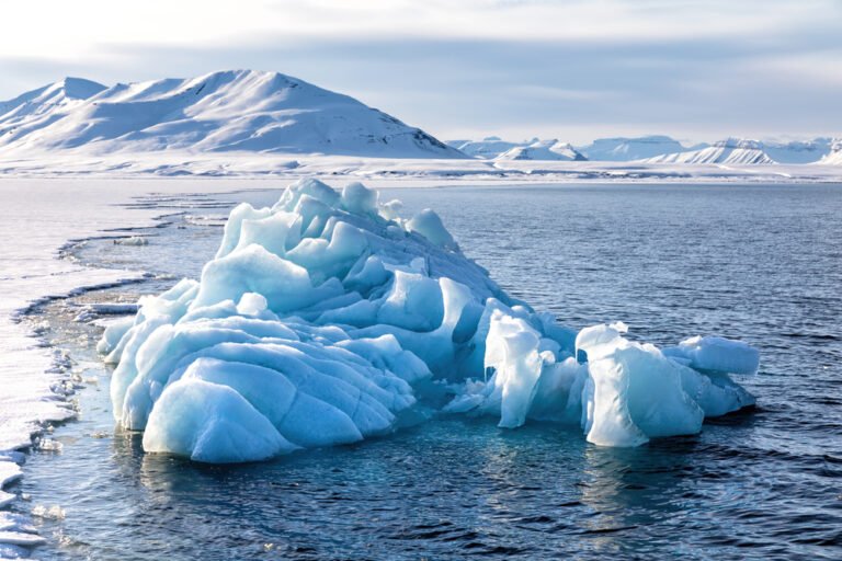 Blue glacial iceberg at the edge of the fast ice in the Nordfjord, Svalbard.